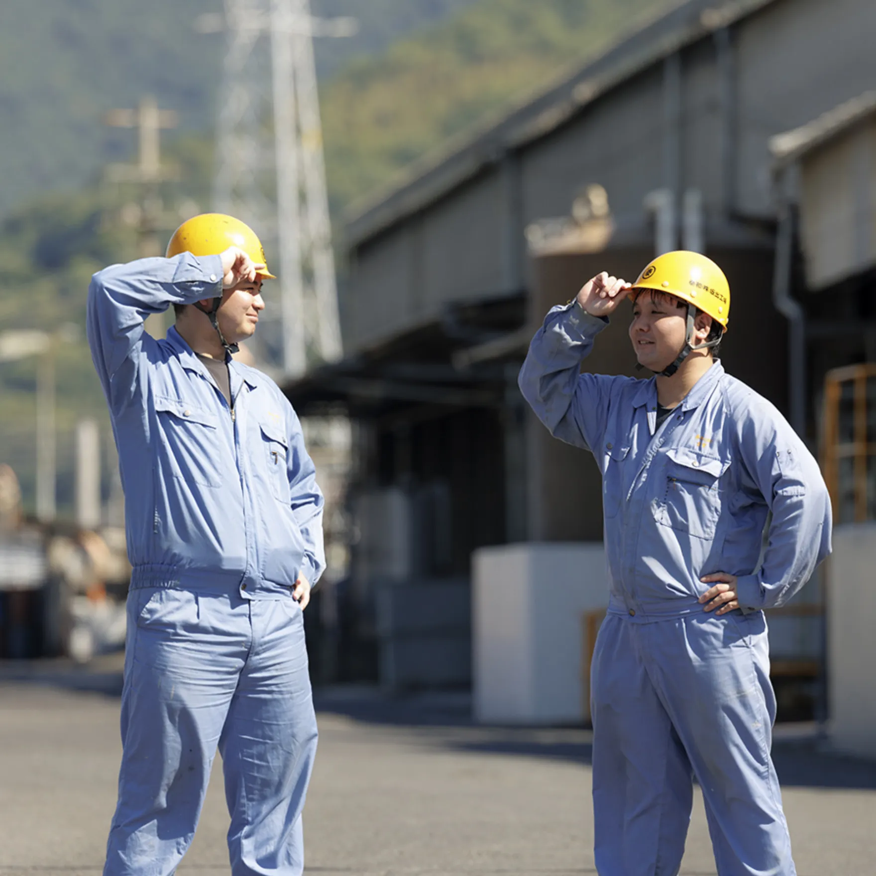 野外でヘルメットに手をかける男性作業員たち