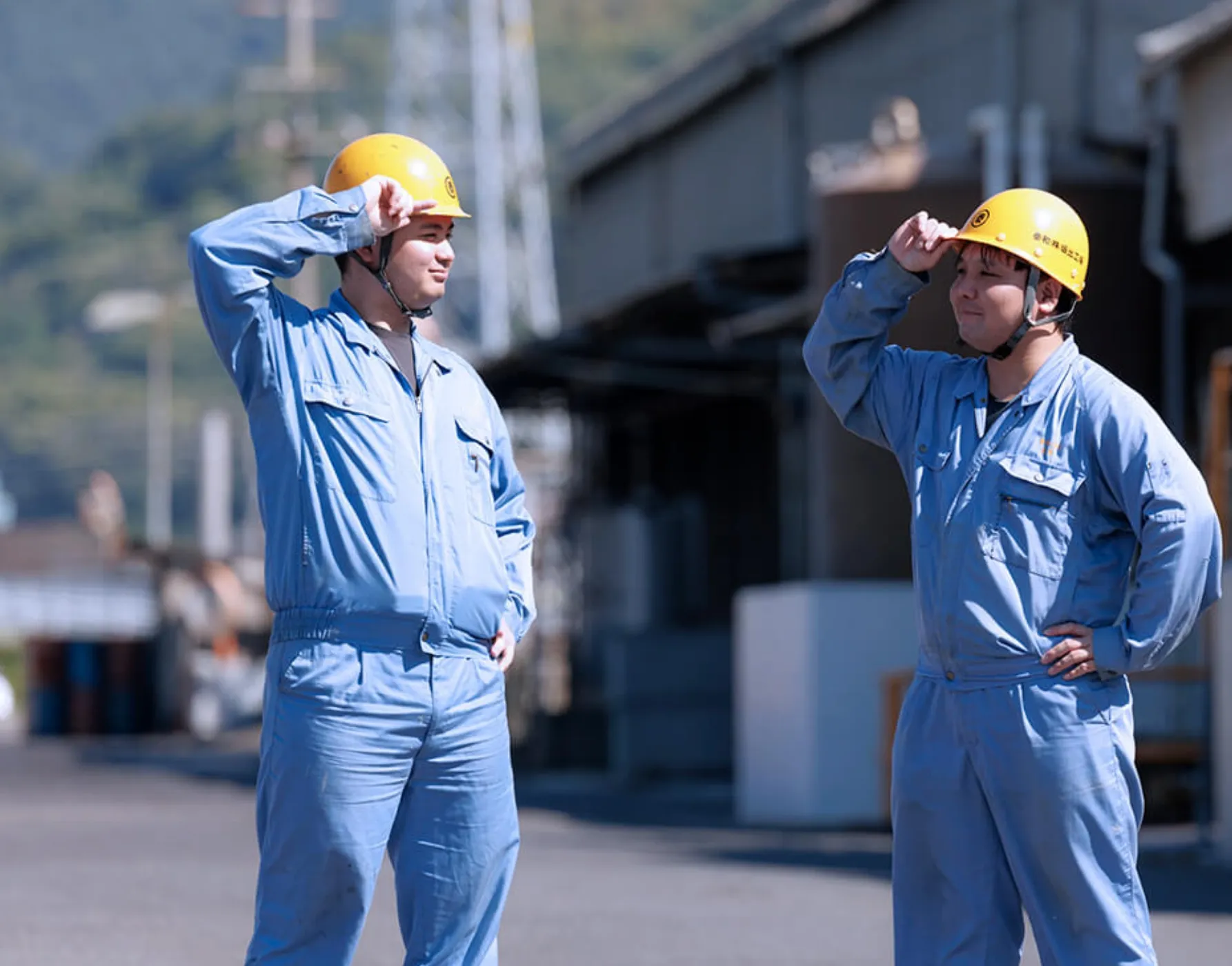 野外でヘルメットに手をかける男性作業員たち