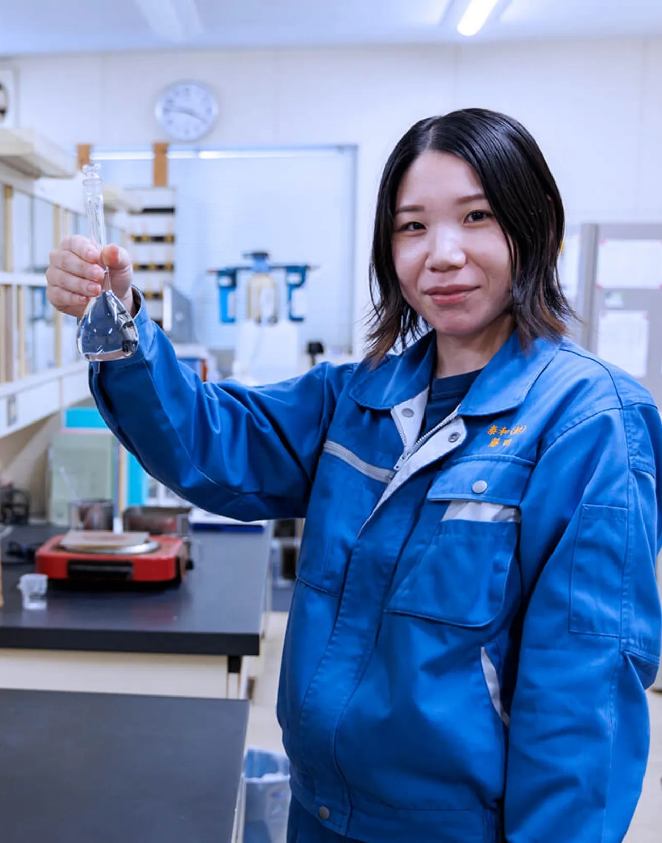 フラスコを持つ作業着の女性社員