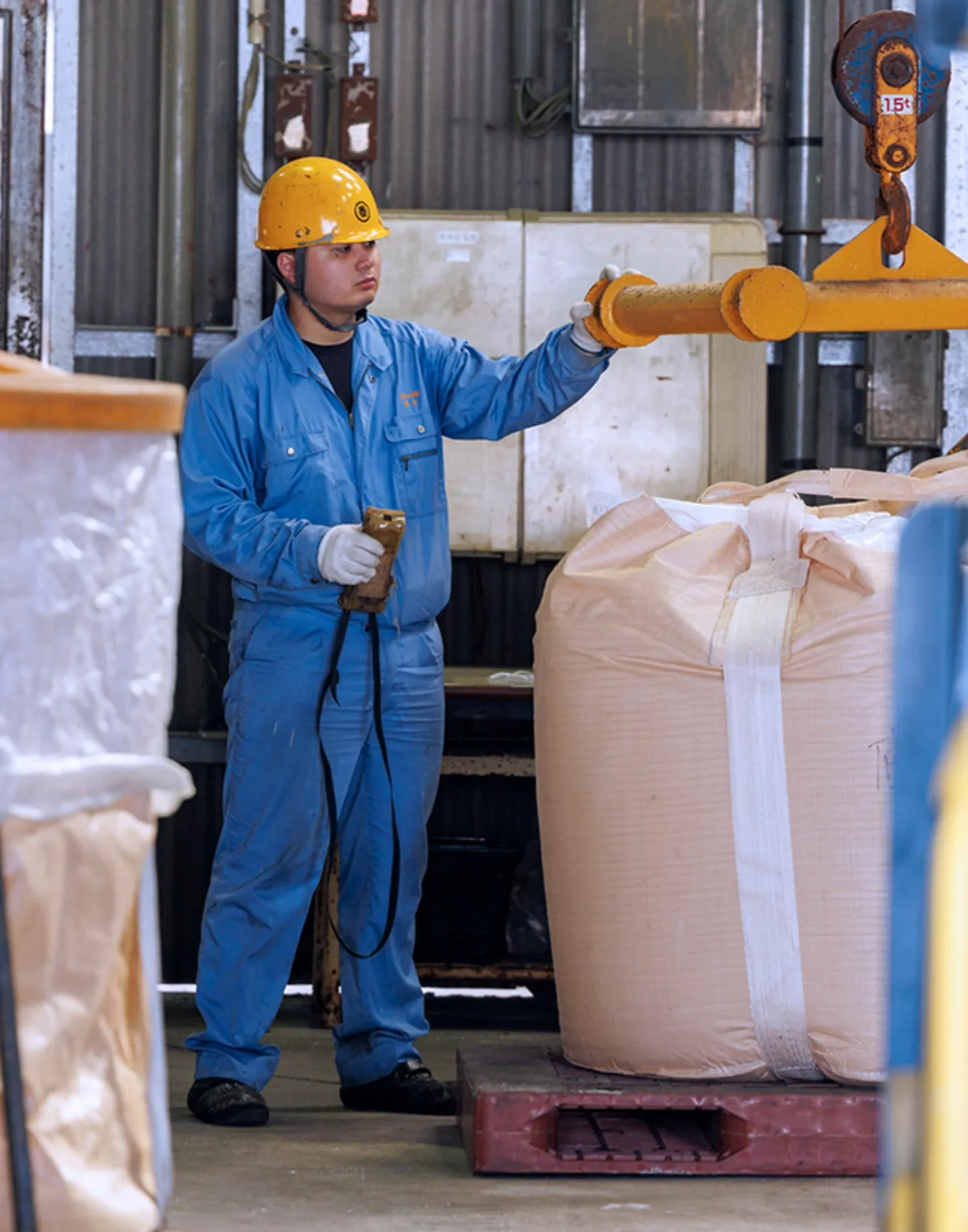 工場でフレコンバッグをクレーンで運ぶ作業員
