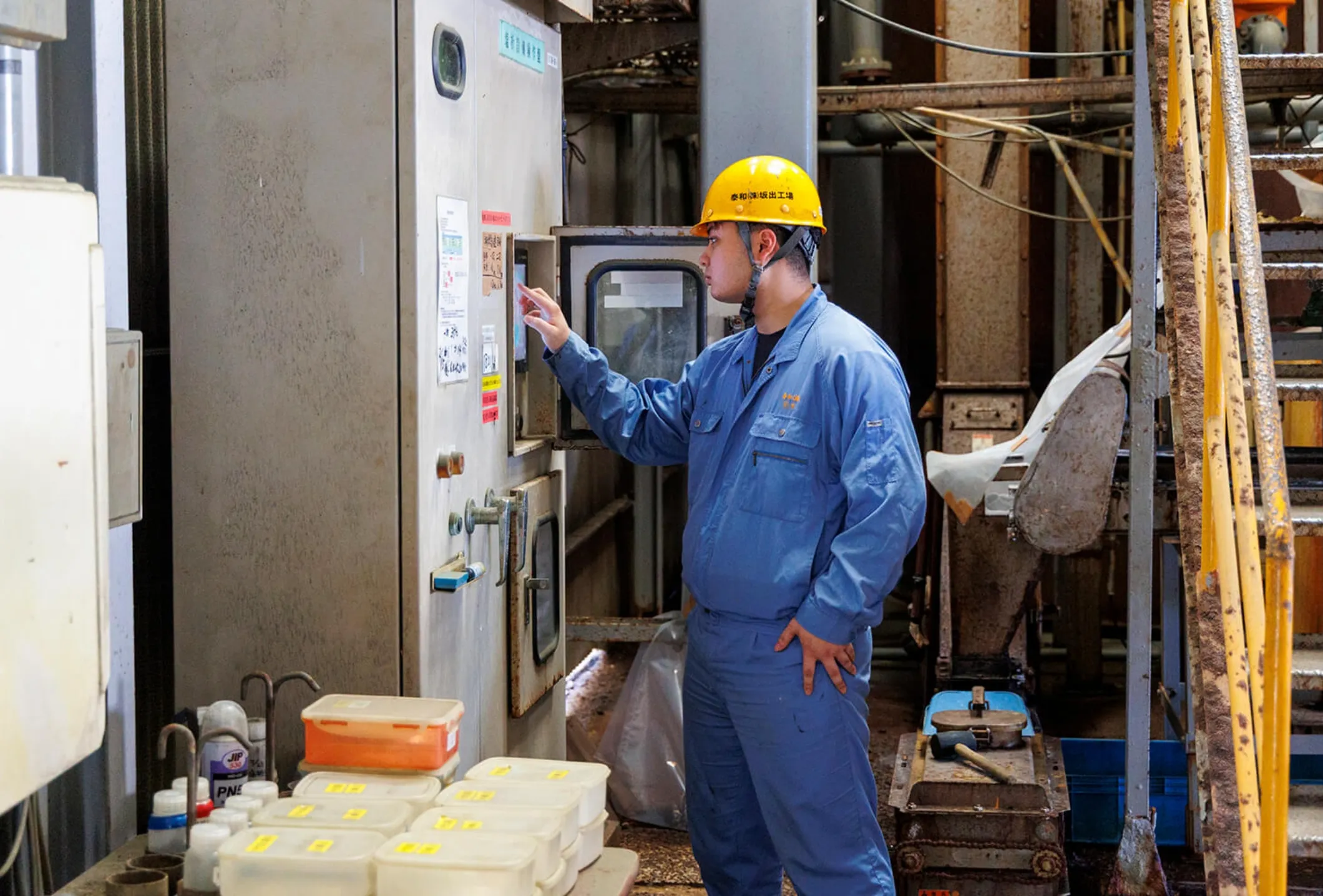 工場内で制御盤を操作する男性社員