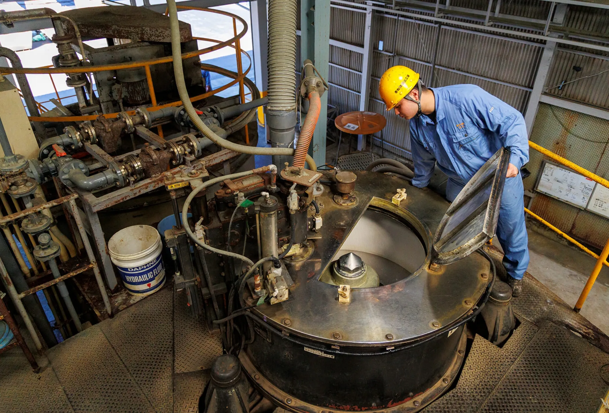 工場内で大型装置の内部を点検する男性社員