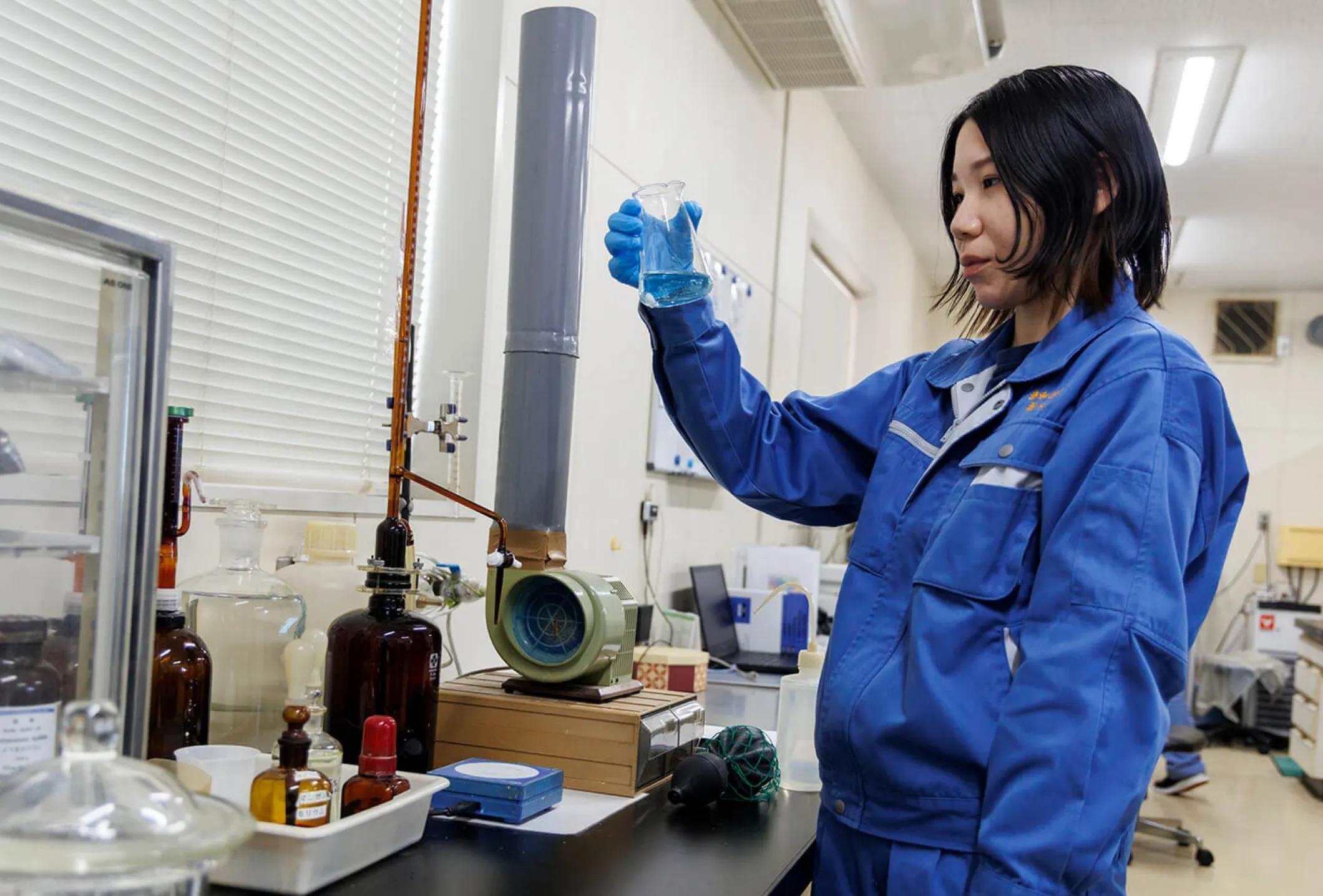 ビーカーの液体を観察する女性社員